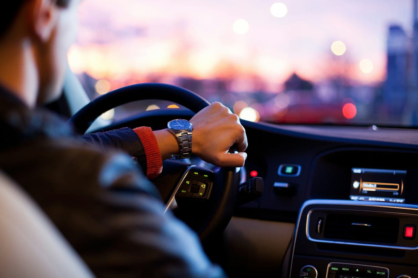Les mains d'un chauffeur sur le volant en fin de journée.